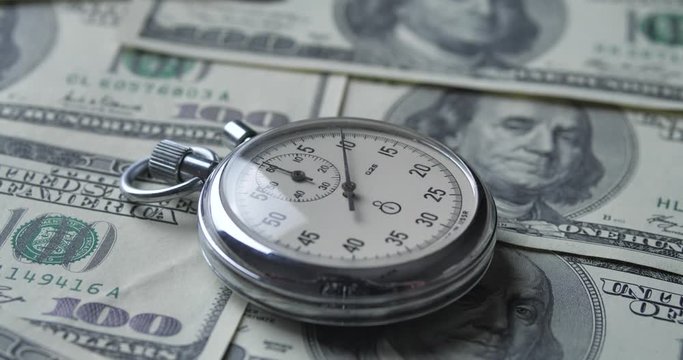 The stopwatch lies on the dollars. Time is money concept.
