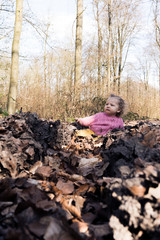 petite fille joue dans les bois, feuilles et ornières