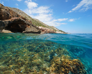 Mediterranean sea rocky coast in Spain with fish underwater, split view over and under water surface, Costa Blanca, Denia, Alicante, Valencia