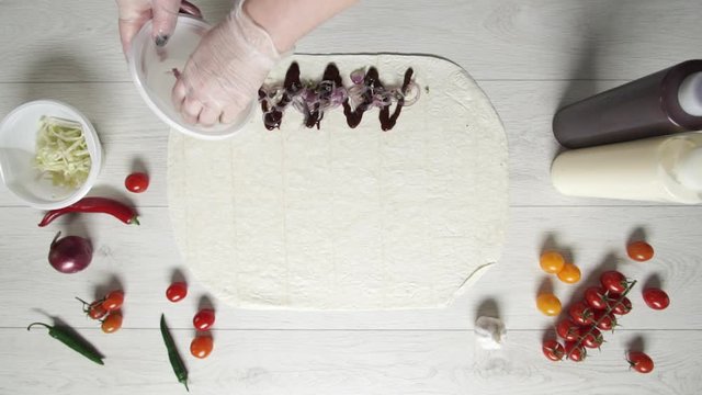 Chef hands in white gloves puts pickled onion on doner kebab shawarma in pita or lavash. Cooking shawarma with chicken, french fries, cheese and vegetable