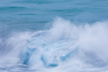 Fototapeta premium Wave splashing against glacier ice outside Jokulsarlon, Iceland.