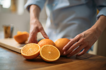 Young woman making juice from fresh oranges at home
