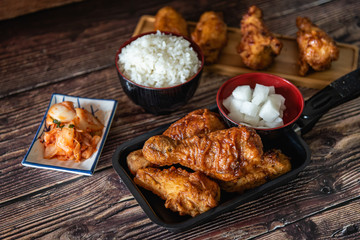 Closed up home made fried chicken with Korean source with garlic, spicy and steamed rice on wooden background, Korean food