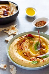 Classic hummus in a bowl with herbs, smoked paprika, olive oil and lettuce on a blue (gray) background. Healthy vegan food. A dish of Middle Eastern cuisine. Healthy eating concept.