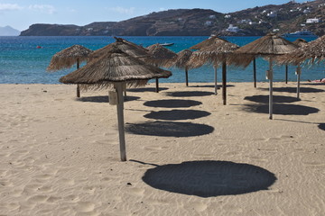 Greece the island of Ios. Sun umbrellas cast a shadow onto the pale sand beach. The summer is winding down to autumn so there are no sunbeds being used. 