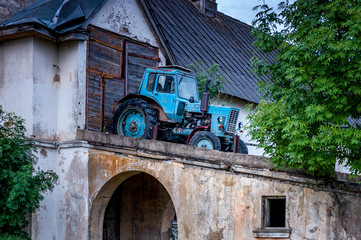 Fototapeta na wymiar Vintage agricultural tractor on old warehouse background.