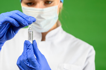 A medical worker in a protective suit holds an ampule with a coronavirus vaccine