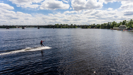 Fototapeta na wymiar The guy in a thermosuit rides a board on water in the local river. Modern sport.