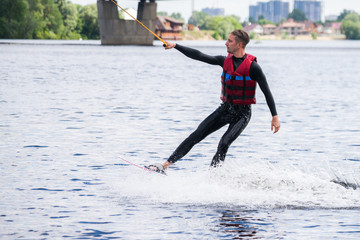 The guy in a thermosuit rides a board on water in the local river. Modern sport.