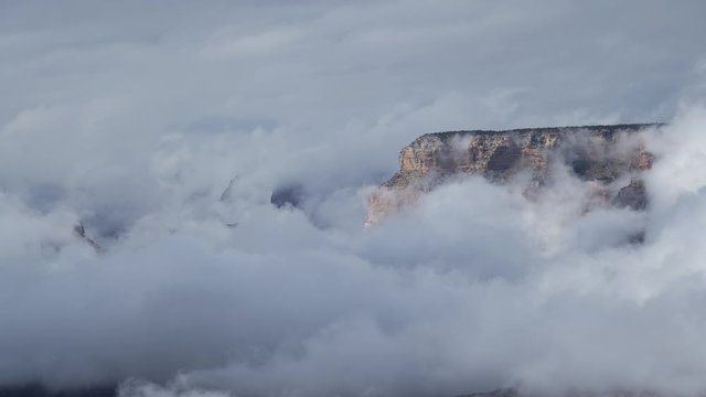 A stunning long-lens timelapse of clouds flowing in front of the distant North Rim of the Grand Canyon. The distant cliffs are revealed and hidden by the passing cloud.