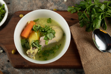 Chicken soup with herbs and green salad,a spoon around