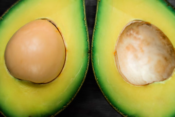 Macrophotography of a ripe avocado halves lying on a wooden brown background with copy space. One...
