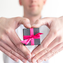 Homme tenant un cadeau dans ses mains en forme de coeur