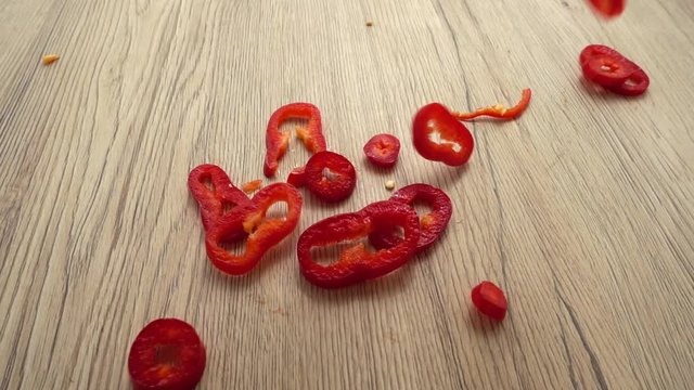 Chopped red capi pepper falls on a wooden board. Slow motion.
