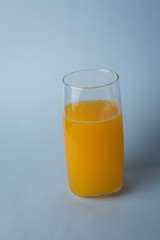 Jugo de nanja fresco con trozos de naranja sobre un fondo azul