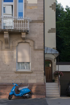 Motorroller vor dem alten Gründerzeithaus mit Rundbogenfenstern
