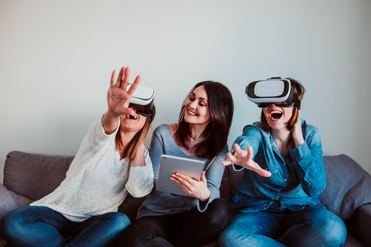 .Group Of Three Friends And Roommates Playing A Virtual Reality Game, Wearing Vr Glasses. Fun And Relaxed During Quarantine Days At Home. Lifestyle