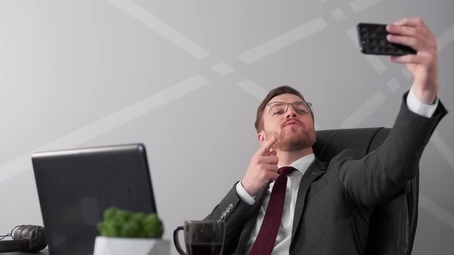 businessman in chair taking selfie on phone