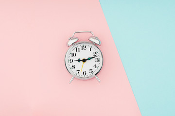Metal vintage alarm clock on of colorful paper background. Time and planning minimal flat lay concept