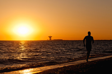 Fototapeta na wymiar Man running on tropical beach at sunset