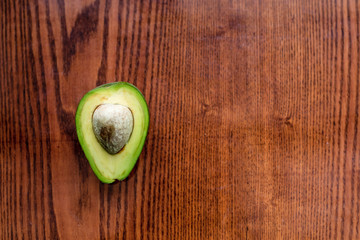 A half of fresh organic green avocado with nucleus isolated on dark textured wooden surface.Healthy...