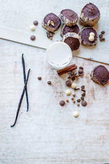 Tasty homemade cookies with a glass of milk and spices:vanilla pod, cinnamon, cloves, crisps,coffee beans,drops of white and black chocolate lying on a white wooden vintage background.