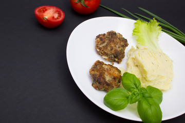 Homemade cutlets with mashed potatoes and vegetables. Top view on black background