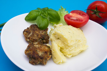 Homemade cutlets with mashed potatoes and vegetables. Top view on blue background