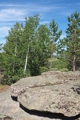 The rock with small green trees near it, the blue sky with white cloud