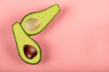 Green half avocadoes isolated on pink background, with and without seed