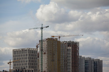 Fototapeta na wymiar Construction site with cranes against the cloudy sky