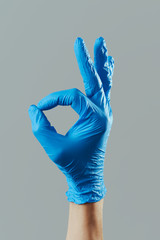 man wearing surgical gloves doing the OK sign