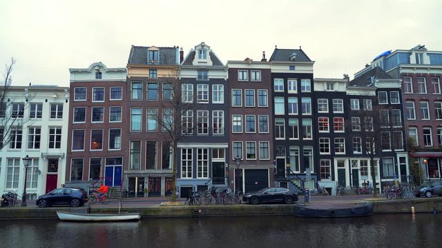 Buildings in Amsterdam city embankment downtown without tourists and people due to Coronavirus Covid-19 and only food deliverers on bikes , Netherlands
