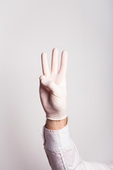 Male hand in a medical glove shows three fingers on a white background