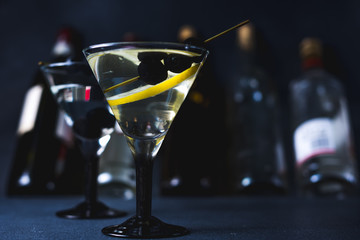 Dry martini with black olives and fresh lemon.Vermouth cocktail inside martini glass over dark...