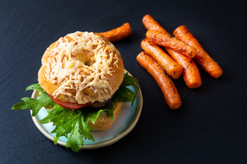 Food bakery concept Homemade organic bagel vegetarian sandwich roasted eggplant rocket and  roasted carrots on black slate stone background