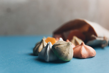 Colorful meringues and a small cloth bag decorated with white snowflakes on a blue background. Selective focus