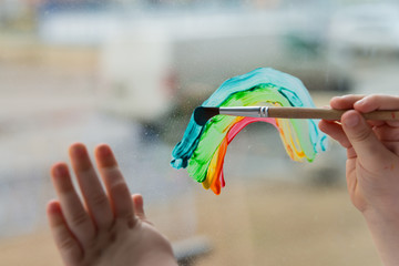  child at home draws a rainbow on the window
