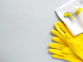 Yellow cleaning gloves with napkin, spray bottle on grey background. Concept cleaning and disinfection room, office, apartments. Copyspace, flat lay, layout, top view