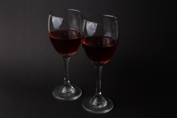hermosas copas de vino transparentes con vino tinto sobre un fondo negro