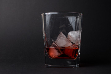 Vaso pequeño con hielo y whiskey en un fondo negro