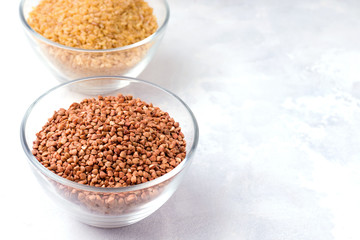 Buckwheat groats in a glass bowl on concrete background. Copy space.