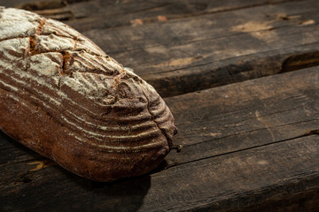 Fresh baked bread at brown wooden table. brown coarse grain bread.