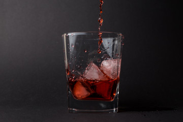 Vaso pequeño con hielo y whiskey en un fondo negro