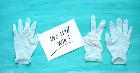 Fight the coronavirus, medical gloves with message - we will win - health care system improvement symbol picture with victory sign