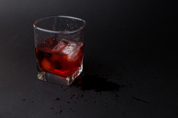 Vaso pequeño con hielo y whiskey en un fondo negro