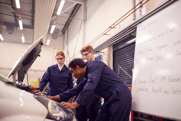 Fototapeta na wymiar Male Tutor With Students Looking At Car Engine On Auto Mechanic Apprenticeship Course At College