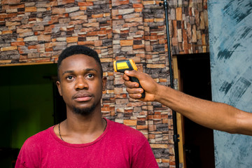 young african man having his body temperature checked with an infrared thermometer