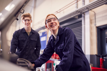 Male And Female Students Looking At Car Engine On Auto Mechanic Apprenticeship Course At College - obrazy, fototapety, plakaty