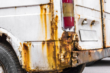 
Rust on the rear wing of a white minibus, old rusty car